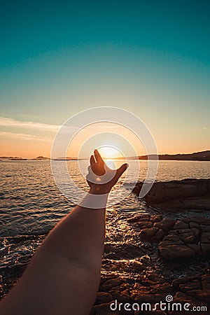 Relaxing image of a male hand in front of a massive sunset in the coastline Stock Photo