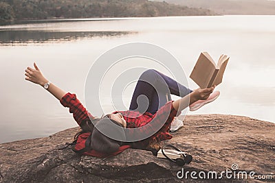 Relaxing moment Asian tourist reading a book on rock Stock Photo