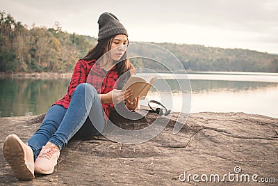 Relaxing moment Asian tourist reading a book on rock Stock Photo