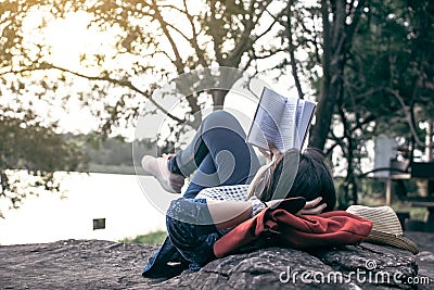 Relaxing moment Asian tourist reading a book on rock Stock Photo