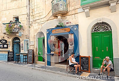 Relaxing people in front of small city cafe on historical street with wooden doors and vintage decorations Editorial Stock Photo