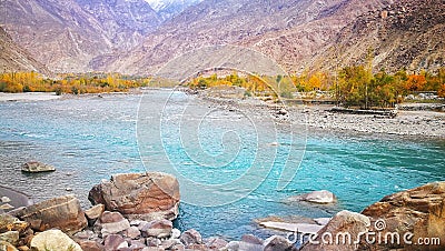 Relaxing scenery of light blue crystal clear water of Gilgit river with red rocky mountains in autumn of Pakistan Stock Photo