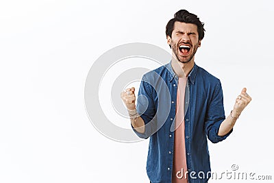 Relieved happy lucky good-looking man achieve prize, winning, dream came true, close eyes and scream from happiness and Stock Photo