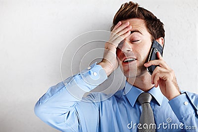 Utter relief after getting the promotion. A relieved young businessman rubbing his face while taking a call. Stock Photo