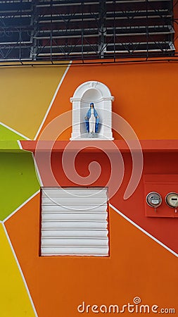 Religious statue on bright colored orange building in Yauco, Puerto Rico Stock Photo