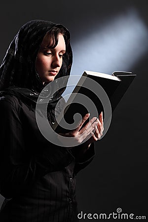 Religious young woman in headscarf reading bible Stock Photo