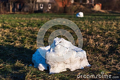 Remains of a melted snowman. A big dirty snow ball that melts in the spring. Arrival of spring on a background of green grass Stock Photo