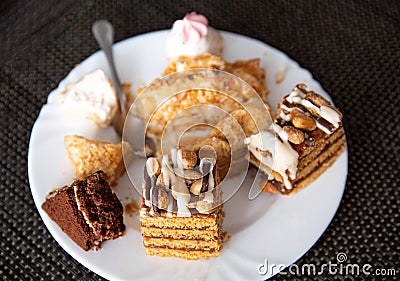 The remains of pastries and cake in a plate on the table. Harmful delicious sweet food. Close-up, finished Stock Photo