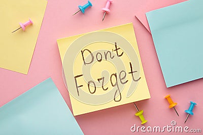 Reminder with text `Don`t forget` on a yellow memo on pink background Stock Photo