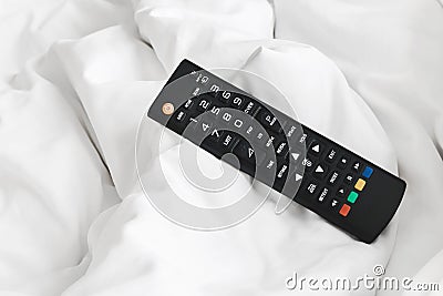 Remote on bed sheets Stock Photo