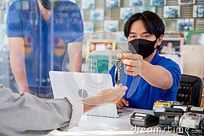 Remote car key that is sent by automotive shop worker to the customer who give hand to receive the key in the area of counter Stock Photo