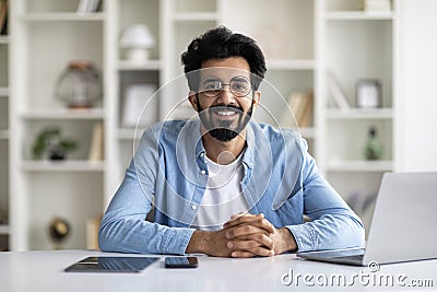 Remote Career. Smiling Indian Male Freelancer Posing At Desk In Home Office Stock Photo