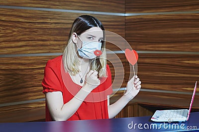 Remote dating during quarantine. Virtual love on Valentine's Day. Girl in medical mask with a paper heart during Stock Photo