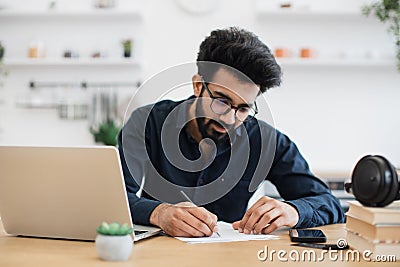 Remote employee making notes on paper in workplace at home Stock Photo