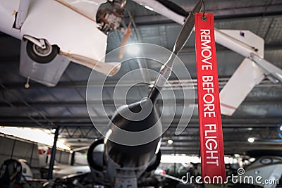 Remove Before Flight red ribbon hanging off fighter jet in hangar. Stock Photo