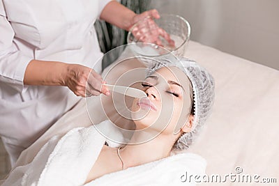 Remove with spatula foam from the face. Young pretty woman receiving treatments in beauty salons. Facial cleansing foam Stock Photo