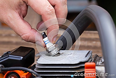 Removing the spark plug from the chainsaw cylinder. Replacing a new spark plug, a malfunction in the ignition of the Stock Photo