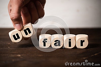 Removing two blocks with letters to change the word unfair to fair Stock Photo