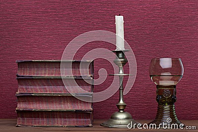 Renaissance, rummer wine glass, old books and candle holder Stock Photo