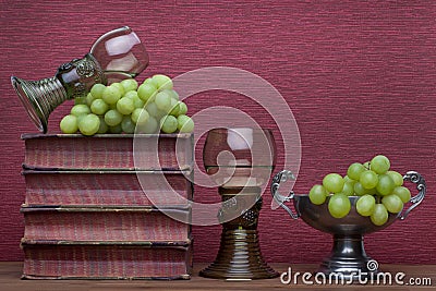 Renaissance, rummer wine glass, old books, tin cup and grapes Stock Photo