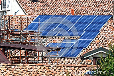 Renewable clean green energy saving efficient photovoltaic solar panels on multiple gable suburban house roof over blue Stock Photo