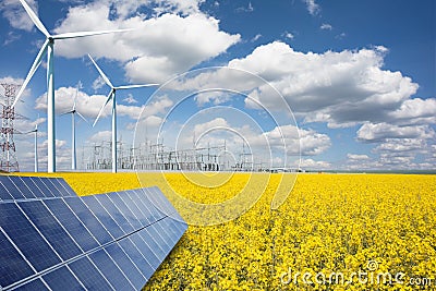 Renewable or green energy concept with wind turbines solar panels and yellow raps field on blue sky with clouds Stock Photo