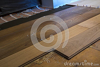 Renovation works. Close-up of installation of parquet and ceramic tile floor and heating cables for warm floor. Stock Photo