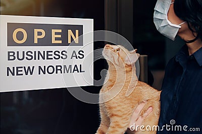 Reopening for business adapt to new normal in the novel Coronavirus COVID-19 pandemic. A cat with their owner person wearing mask Stock Photo