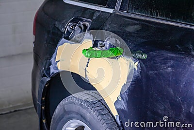 Repair of car body parts in black after an accident and scratches by applying a yellow putty to damaged areas and taped Stock Photo