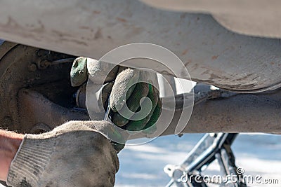 Repair of the car suspension. Gloved hand. Replacing the shock absorber strut Stock Photo