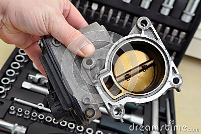 Repair and cleaning the car throttle. Throttle with traces of burning and soot on the background of a set of tools Stock Photo