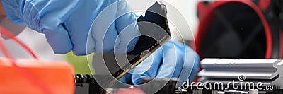 Repair engineer holds RAM chip with hands and inserts RAM of computer into socket of computer motherboard Stock Photo