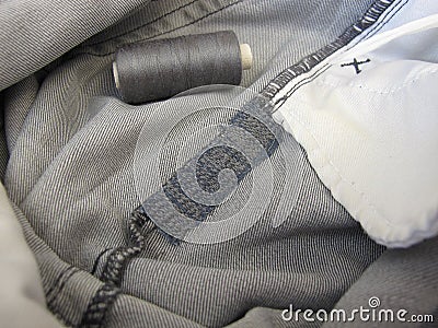 Repair garments, stitched seams on a worn jeans trousers with the sewing machine Stock Photo
