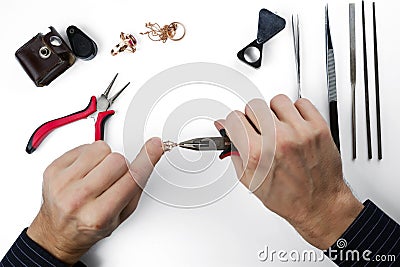 Repair of gold jewelry. Hands of the jeweler with tools and jewellery isolated on white Stock Photo