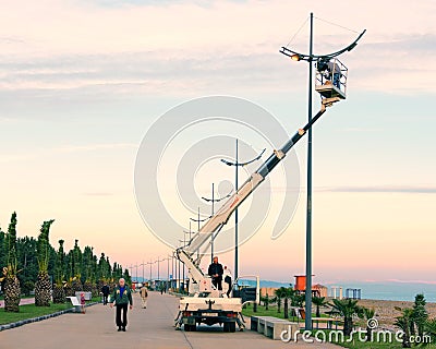 Repair and maintenance of street lamps in city park street at sunset in evening - crane lifted electrician to replace light bulb Editorial Stock Photo