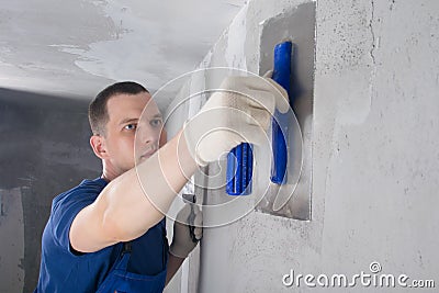 Repair master of concrete walls, plasters the joint of the wall with the ceiling, close-up Stock Photo