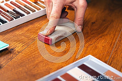 Repair and restoration of laminate and parquet. sealing scratches and chips. the master erases a working wooden surface close-up Stock Photo