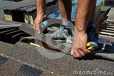 Repair of a Roofing from shingles. Roofer cutting roofing felt or bitumen during waterproofing works. Roof Shingles - Roofing. Stock Photo