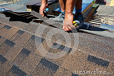 Repair of a Roofing from shingles. Roofer cutting roofing felt or bitumen during waterproofing works. Roof Shingles - Roofing. Stock Photo