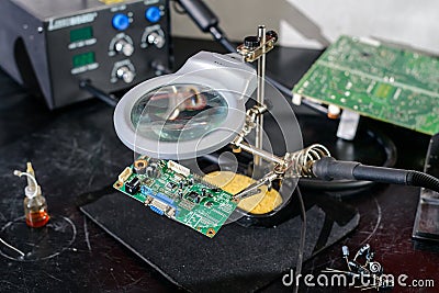 Repair shop of electronic equipment, soldering station, magnifier and third hand Stock Photo