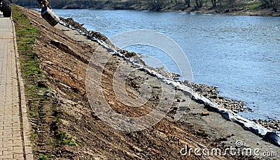 Repair of the slope above the river, the river banks are strengthened by a bunch of stonemasons where the embankment is paved with Stock Photo