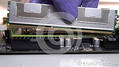 The repair technician inserts a RAM stick into the socket on the motherboard. Maintenance and modernization of a Stock Photo