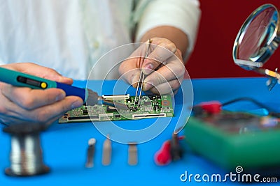 Repair of the video converter board of the TV signal. Soldering of electronic components by an engineer of modern TVs. Stock Photo