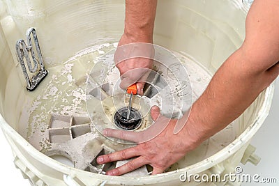 Repair of washing machines, repair of large household appliances. Repairman disassembles a washing machine for parts Stock Photo