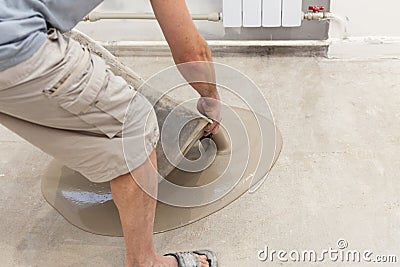 Repair work. Pouring floors in the room. Fill screed floor repair and furnish. Worker pouring concrete on the floor Stock Photo