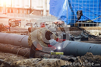Repairing of city water supply or sewer pipeline. Worker is welding pipe Editorial Stock Photo