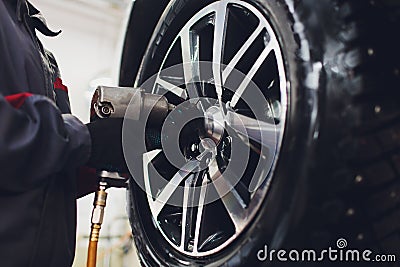 Repairman balances the wheel and installs the tubeless tire of the car on the balancer in the workshop. Stock Photo