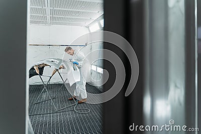 Repairman car painter in chamber painting automobile bumper. Stock Photo