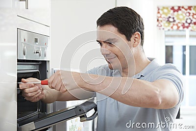 Repairman Fixing Domestic Oven In Kitchen Stock Photo
