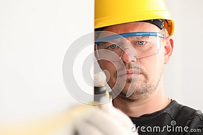 Repairman in helmet and mask, measures tape measure Stock Photo